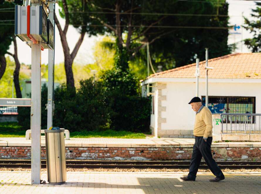 Senior man walking along a railway platform in Madrid, Spain, showcasing urban daily life.