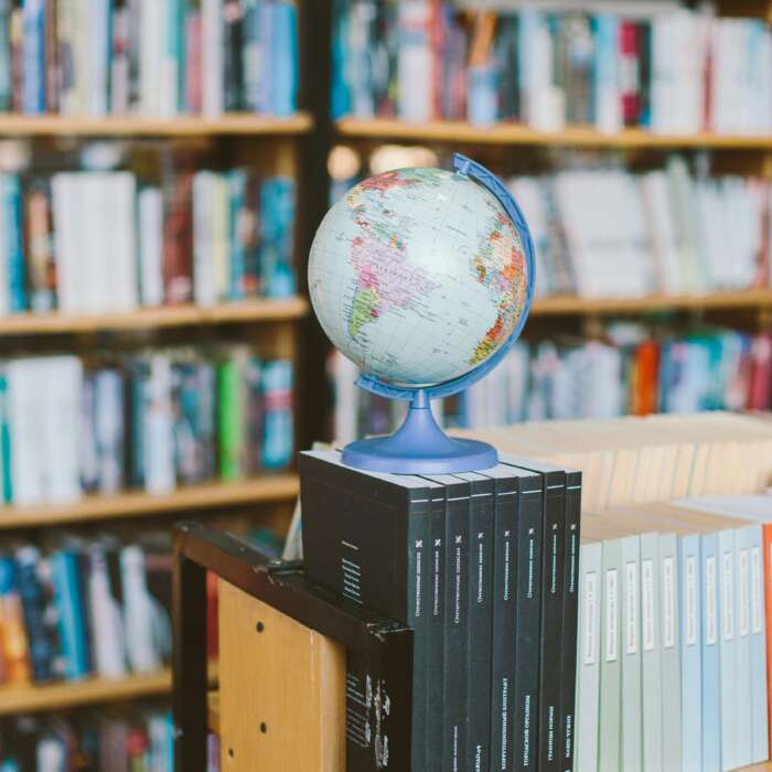 A globe and book stack in a library, symbolizing education and global knowledge.